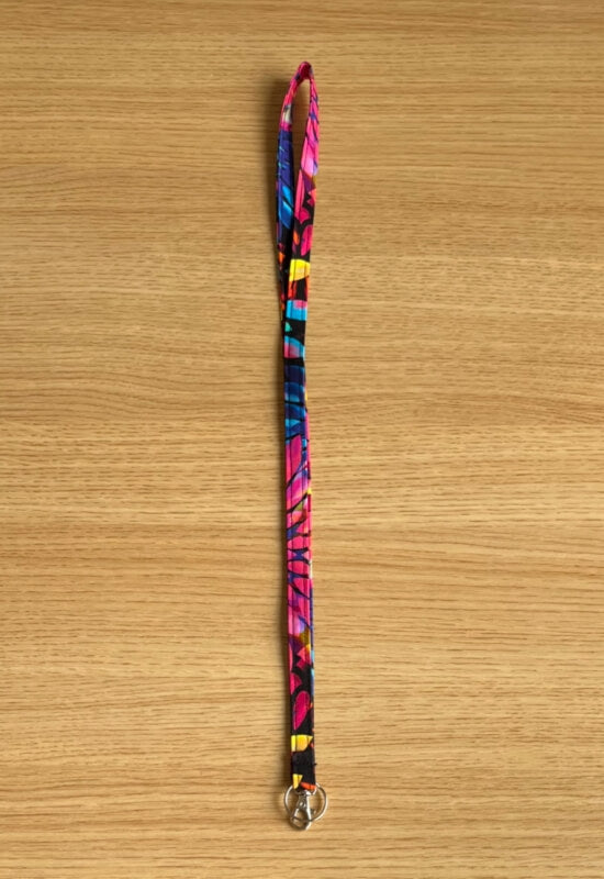 Kaleidoscope Dream lanyard with vibrant multicolor floral print on a black background