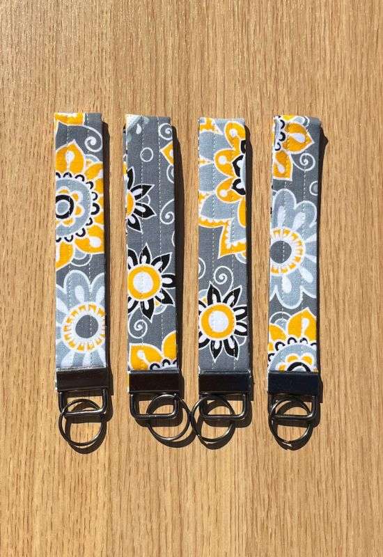 Citrus Garden wristlet keychain with bold yellow and white floral print on dark gray fabric