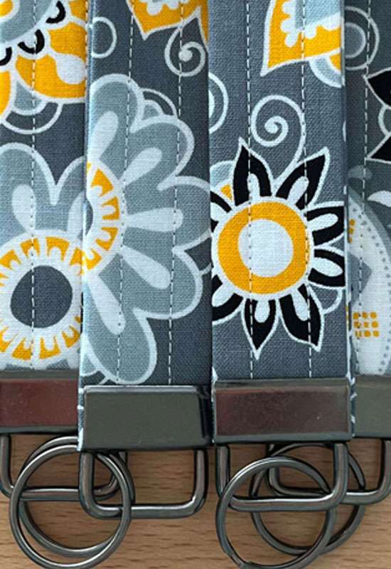 Citrus Garden wristlet keychain with bold yellow and white floral print on dark gray fabric