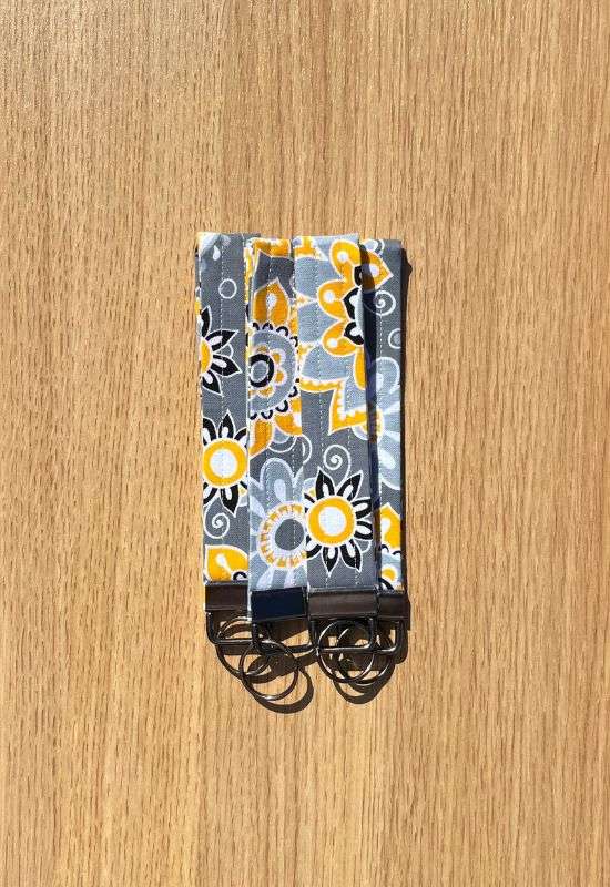 Citrus Garden wristlet keychain with bold yellow and white floral print on dark gray fabric