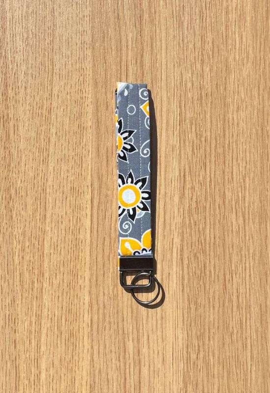 Citrus Garden wristlet keychain with bold yellow and white floral print on dark gray fabric